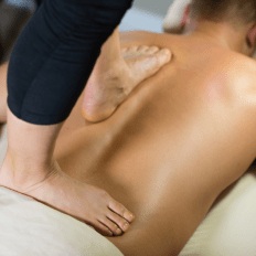 Thai therapist walking on woman's back